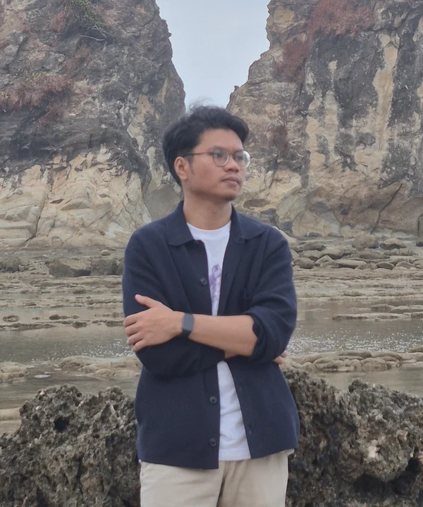 Farhan Rangkuti, arms crossed, on a rocky beach